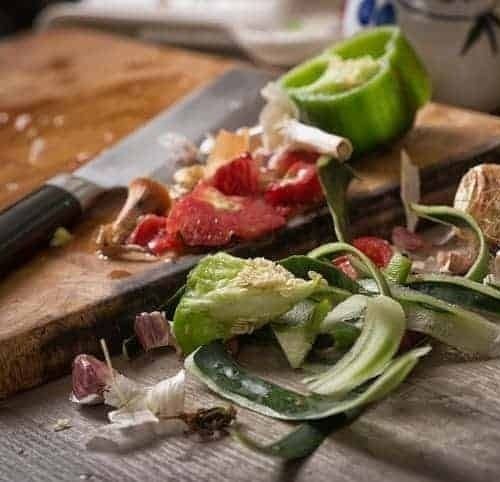 Grönsaksrester och skal samlade på en skärbräda med kniv