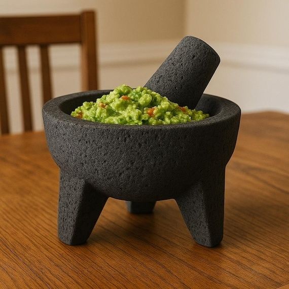 Mörk molcajete med grön, chunky salsa och stöt på träbord